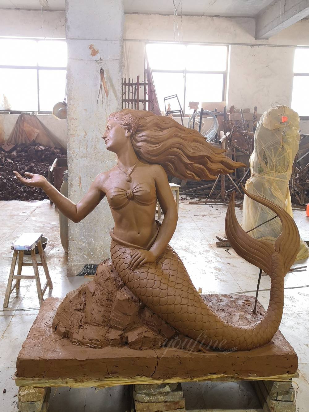 Clay model holding fish garland