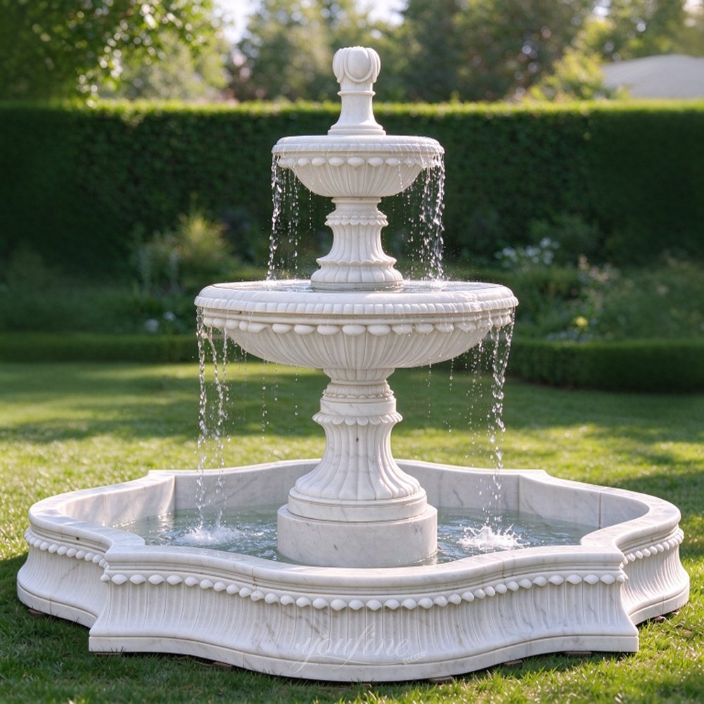 tiered white marble fountain on a garden lawn